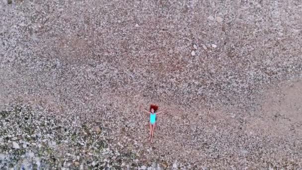 Top uitzicht van jonge vrouw liggend op kiezelstrand in de buurt van zee golven — Stockvideo