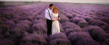 Gündoğumu içinde çiçeklenme lavanta alanının ortasında genç çift ayakta
