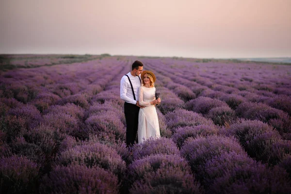 Jeune couple debout au milieu du champ de lavande en fleurs au lever du soleil — Photo