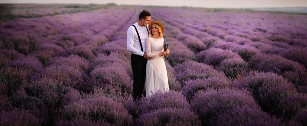 Gündoğumu içinde çiçeklenme lavanta alanının ortasında genç çift ayakta