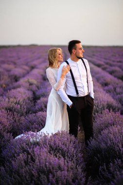Gündoğumu içinde çiçeklenme lavanta alanının ortasında genç çift ayakta
