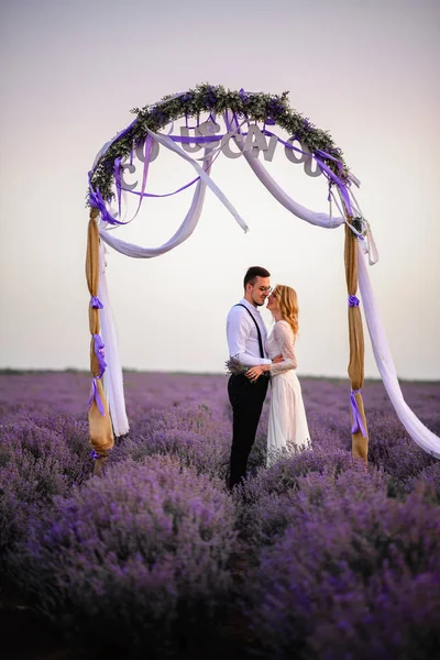 Jeune mariée heureuse et marié étreignant dans le champ de lavande en fleurs — Photo