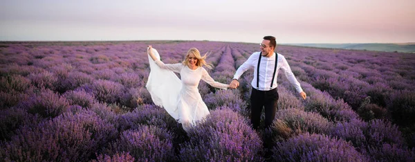 Çiçek açan Lavanta Tarlası boyunca çalışan mutlu yeni evliler