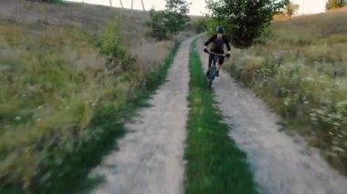 Gün batımında toprak yol boyunca havadan görünüm bisikletçi yarış