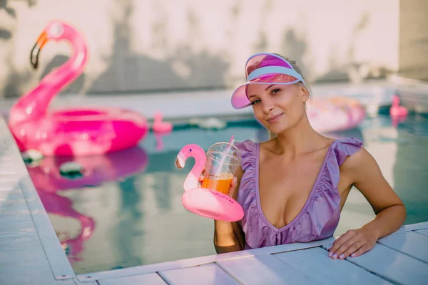 Młoda kobieta w basenie trzyma koktajl w dłoniach i patrzy na kamerę — Zdjęcie stockowe