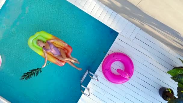 수영복을 입은 젊은 여성이 에어 매트리스에서 수영장에서 수영하는 탑 뷰 — 비디오