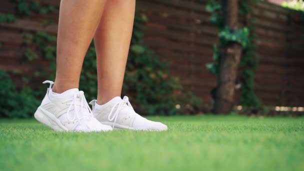 Mulher coloca tapete de fitness na grama, close-up de pernas — Vídeo de Stock