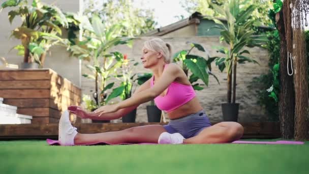 Jonge vrouw doet stretching op gazon thuis, Slow Motion, concept van gezonde levensstijl — Stockvideo