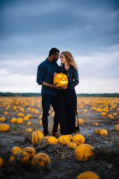 Pareja de pie en el campo de calabaza y la celebración de calabaza cara de miedo, concepto halloween —  Fotos de Stock