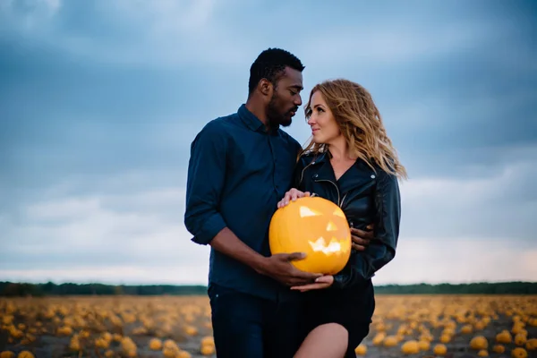 Pareja de pie en el campo de calabaza y la celebración de calabaza cara de miedo, concepto halloween —  Fotos de Stock