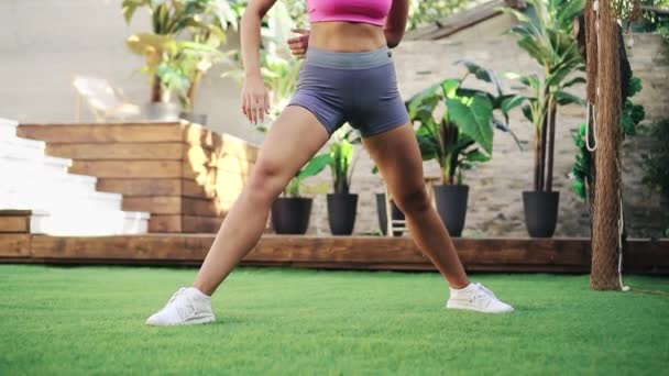 Jeune femme sportive effectue des exercices d'étirement sur la pelouse verte, concept de mode de vie sain — Video