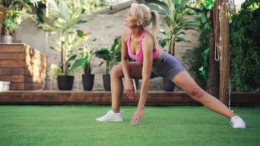 Genç atletik kadın yeşil çimlerde esneme egzersizi yapıyor, sağlıklı yaşam tarzı kavramı.