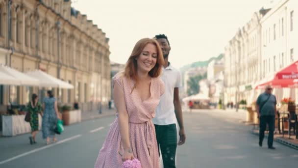 Joven mujer feliz lleva a sus novios mano a lo largo de la calle de la ciudad — Vídeos de Stock