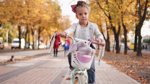Mała dziewczynka jeździ na rowerze na jesiennym bulwarze miasta — Wideo stockowe