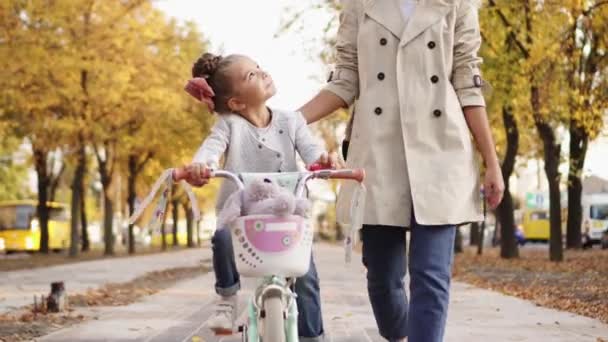 Klein meisje leert fietsen met steun van moeder — Stockvideo