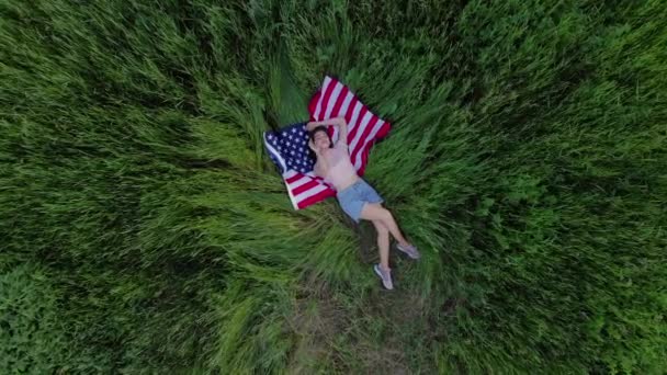 Счастливая девушка лежит на флаге США. — стоковое видео