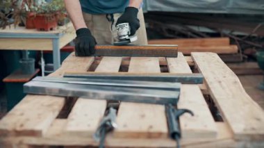 Bir işçi, çelik bir parçanın pasını öğütücüyle öğütüyor. Yakın plan..