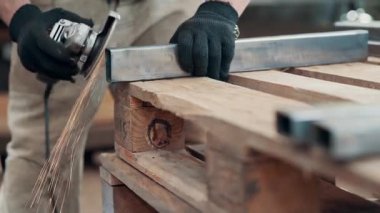 Kaynaklanmış eklemlerin öğütülmesi. Bir adam, metal bir ürünü, bir açı öğütücüyle işliyor. Yakın plan..