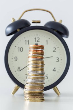bir çalar saat arka plan üzerinde sikke yığını