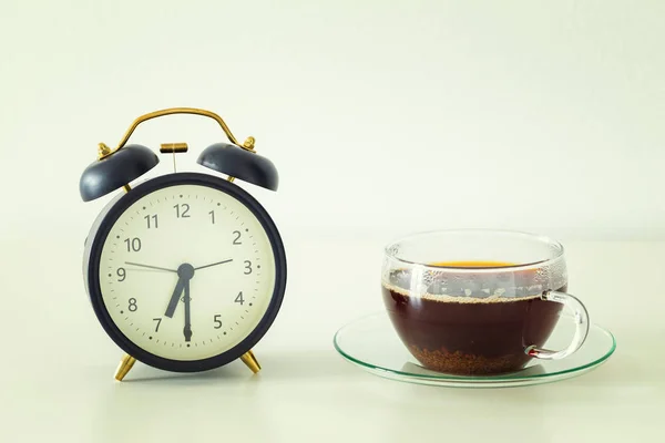 Alarm clock and a glass of tea on the table