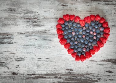 Orman meyvesi, ahududu ve çilek bir kalp şeklinde düzenlenmiş/metin için boş bir yer