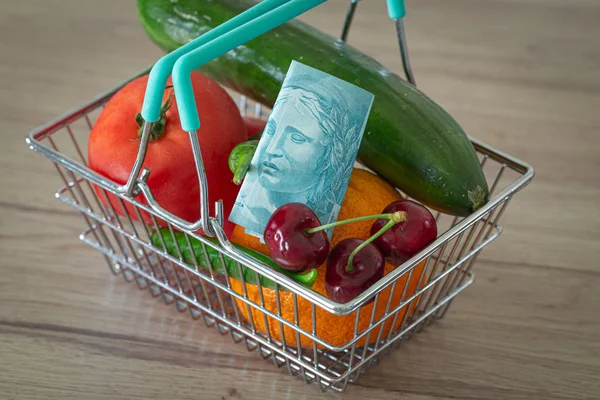 vegetables and fruits in the shopping basket along with brazilian money / the concept of food price increase