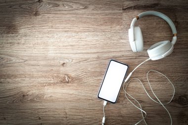 Masada bağlı kulaklıkları olan telefon, metin için yer