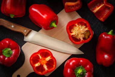 Kırmızı biber. Sağlıklı sebzeler, bütün ve kesilmiş. Koyu arka plan