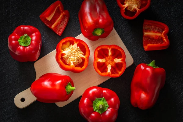 Kırmızı biber. Sağlıklı sebzeler, bütün ve kesilmiş. Koyu arka plan
