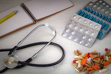 Doktorun masasında steteskop olan büyük miktarda ilaç. Kavram