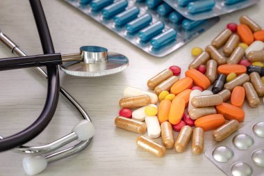 Doktorun masasında steteskop olan büyük miktarda ilaç. Kavram