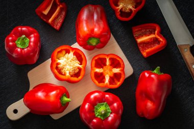 Kırmızı biber. Sağlıklı sebzeler, bütün ve kesilmiş. Koyu arka plan