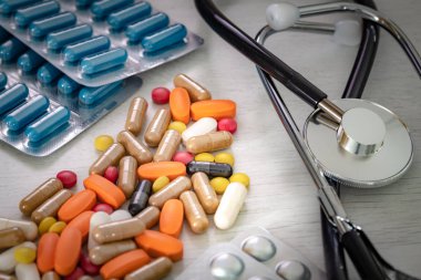 Doktorun masasında steteskop olan büyük miktarda ilaç. 