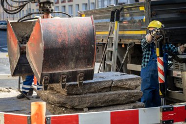 İnşaat yolda yapılıyor. Daha küçük belediye işleri için kazıcı, borular ve yeraltı hatları onarımı