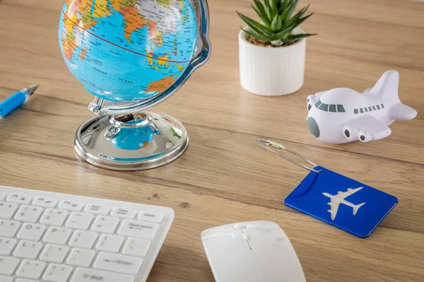 Desk with aviation and travel items. Globe, toy plane, Luggage tag, Computer keyboard, Air travel planning concept