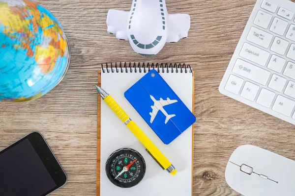 Desk with aviation and travel items. Globe, toy plane, Luggage tag, Computer keyboard, Air travel planning concept