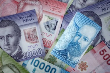 Şili parası, 10.000 peso toplandı, bu ülkenin diğer banknotlarının arka planında yatıyor.