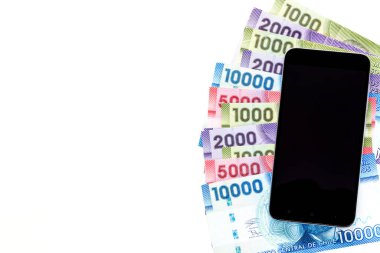 Şili parası, cep telefonuyla birlikte masaya uzanan banknotlar, çeşitli mezhepler, beyaz arka plan, metin için yer