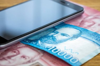 Şili para birimi, peso, banknotlar masanın üzerinde cep telefonuyla yan yana yatıyor.