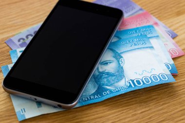 Şili para birimi, peso, banknotlar masanın üzerinde cep telefonuyla yan yana yatıyor.