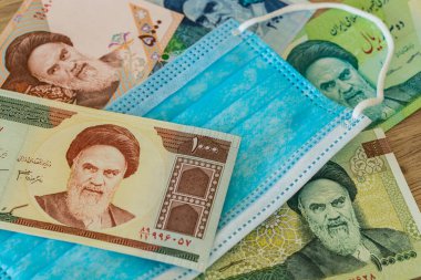 İran parası, anti virüs maskesi. Koronavirüs salgını sırasında ülke ekonomisi kavramı