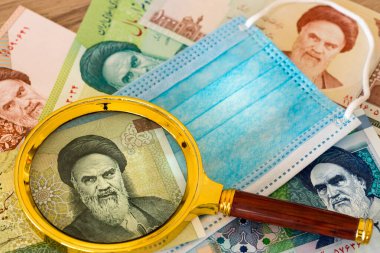İran para birimi, riyal, antivirüs maskesi ve büyüteç. Koronavirüs salgını sırasında ülke ekonomisi kavramı