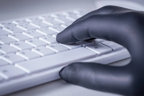 White computer keyboard and hands in black rubber gloves. Concept of crime and harassment on the web