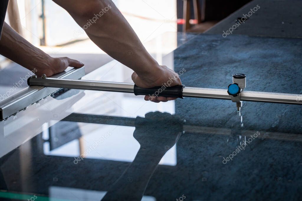 A man cuts the glass with the help of specialized tools in a glass workshop