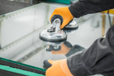 The Glazier uses a sucker for windows. Glass making workshop, The man lifts the pane of thick glass on the table with the help of specialized tools clipart