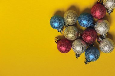  Metin için yer bir sürü ile sarı bir arka plan üzerinde renkli Noel dekorasyon topu. Noel, yeni yıl, tatil, arka planlar kavramı. Noel oyuncaklar.