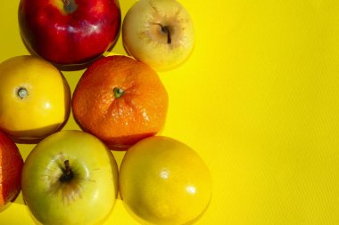 Sarı arka plan üzerinde renkli meyve. Mandalina, limon ve Apple sarı zemin üzerinde. Sağlıklı gıda kavramı.