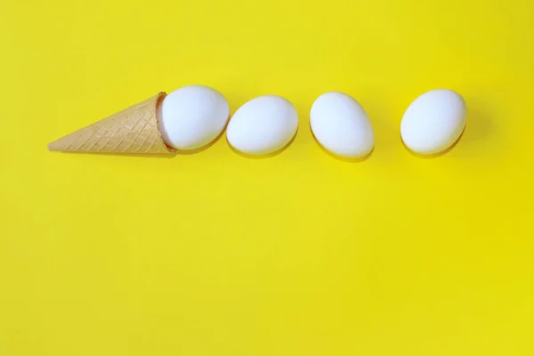 Minimalism, Food, Fashion Style, Easter Concept. Abstract Background. White Eggs In Ice Cream Cone. Minimal Art Design. White Eggs Over Yellow Background. Abstract Colorful Food  Background.