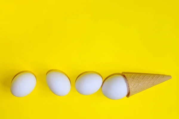 ミニマリズム ファッションスタイル イースターのコンセプトです 抽象的な背景 アイス クリーム コーンの白い卵 ミニマル アートなデザイン 黄色の背景の上の白い卵 — ストック写真
