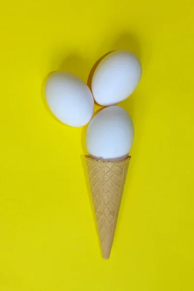 Minimalism, Food, Fashion Style, Easter Concept. Abstract Background. White Eggs In Ice Cream Cone. Minimal Art Design. White Eggs Over Yellow Background. Abstract Colorful Food  Background.